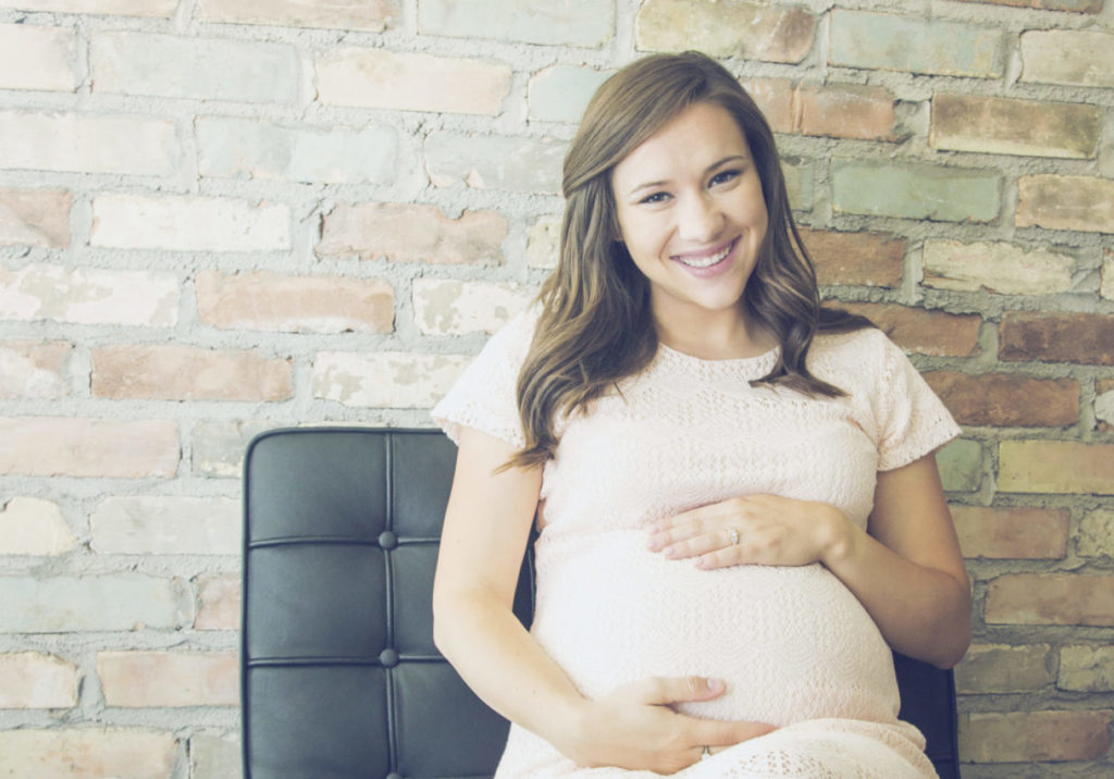 Pregnant women siting in chair with brick wall background