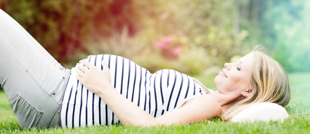 pregnant women laying on the grass