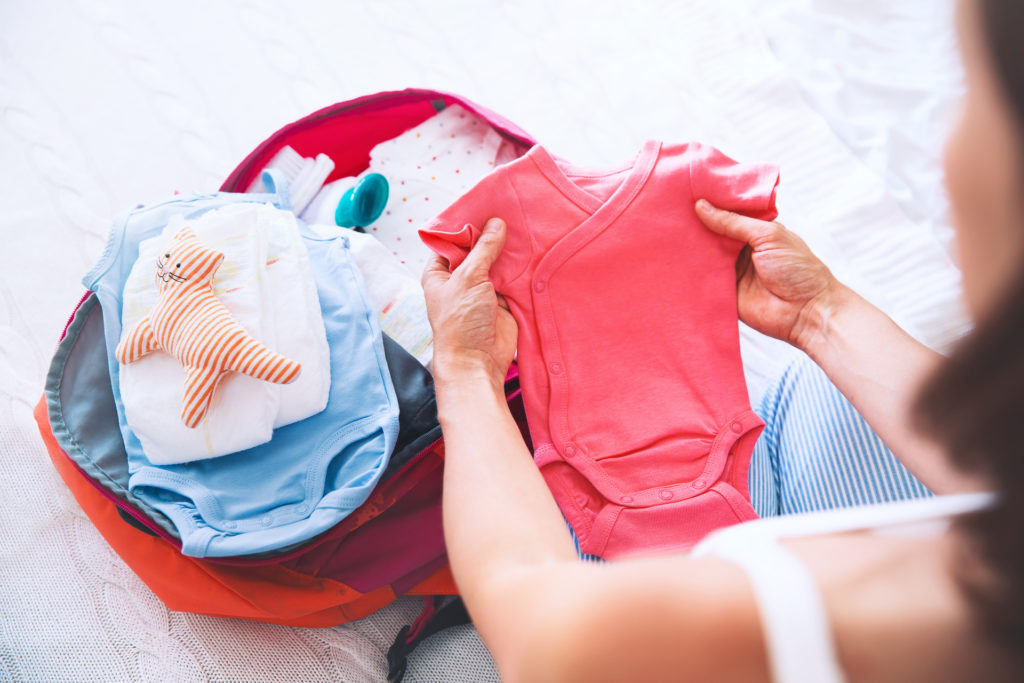 women folding new baby clothes